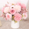 A bouquet of pink and peach silk roses and hydrangeas arranged in a white vase.