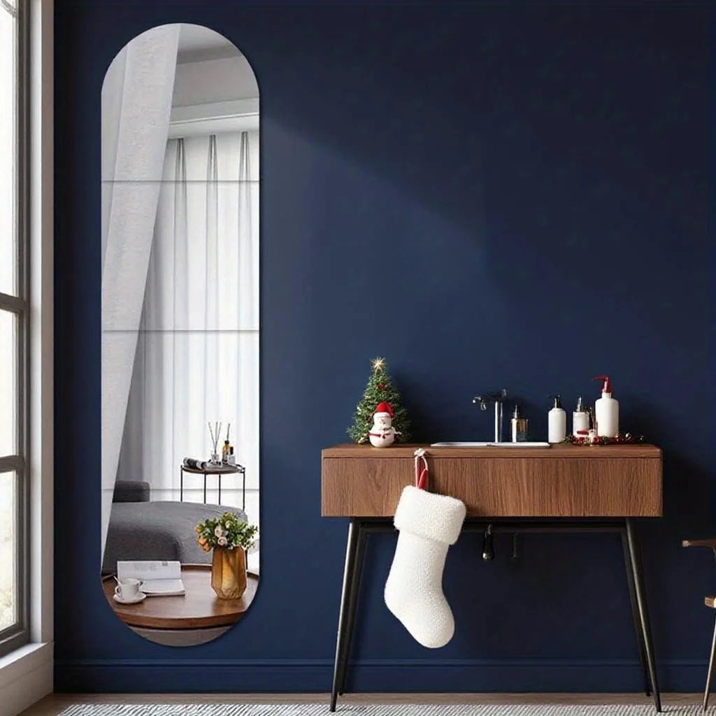 A dark blue wall features a tall arched mirror reflecting white curtains and a wooden console table with decorative items.