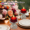 Elegant peony flower shape scented candle surrounded by floral arrangements and candles on a wooden table.