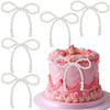 A pink tiered cake decorated with pink frosting and pearl bow toppers.