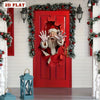 A red door decorated with a festive wreath and a cutout of Santa's face.