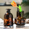 A dark amber glass vase holds a single orange tulip with a green stem.