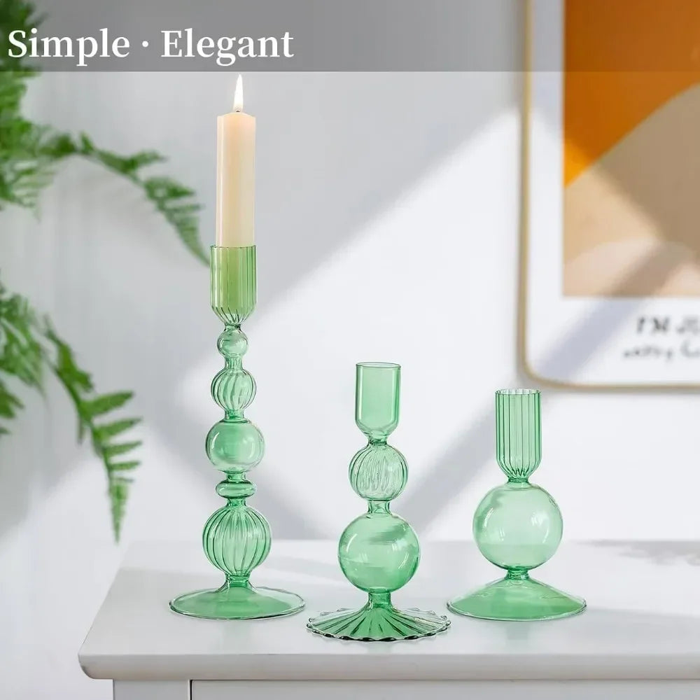 A set of three green wavy glass taper candle holders displayed on a white surface.
