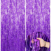 Two vertical panels of metallic purple foil fringe curtains with a hand touching the texture.