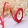 A red satin ribbon scroll forming the letter 'V' and 'O' is placed on a white background surrounded by white flowers.