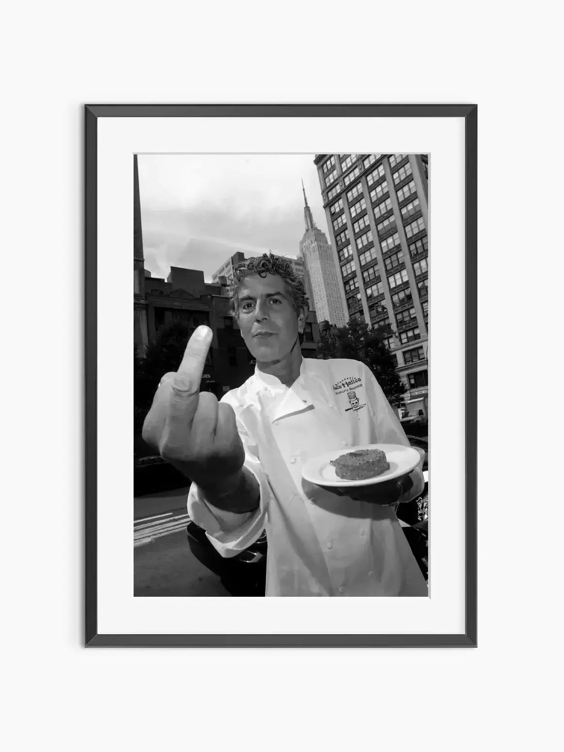 Black and white photograph of a man making a finger sign in front of a city skyline.