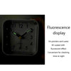 A black digital alarm clock with a fluorescent display showing the time and features for night use.
