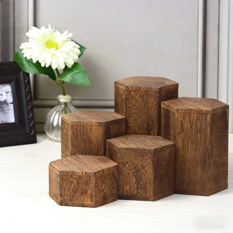 A stack of dark brown wooden hexagonal display racks for jewelry and accessories next to a white flower.