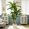A tall artificial Dracaena tree in a white pot displayed in a modern living room setting.