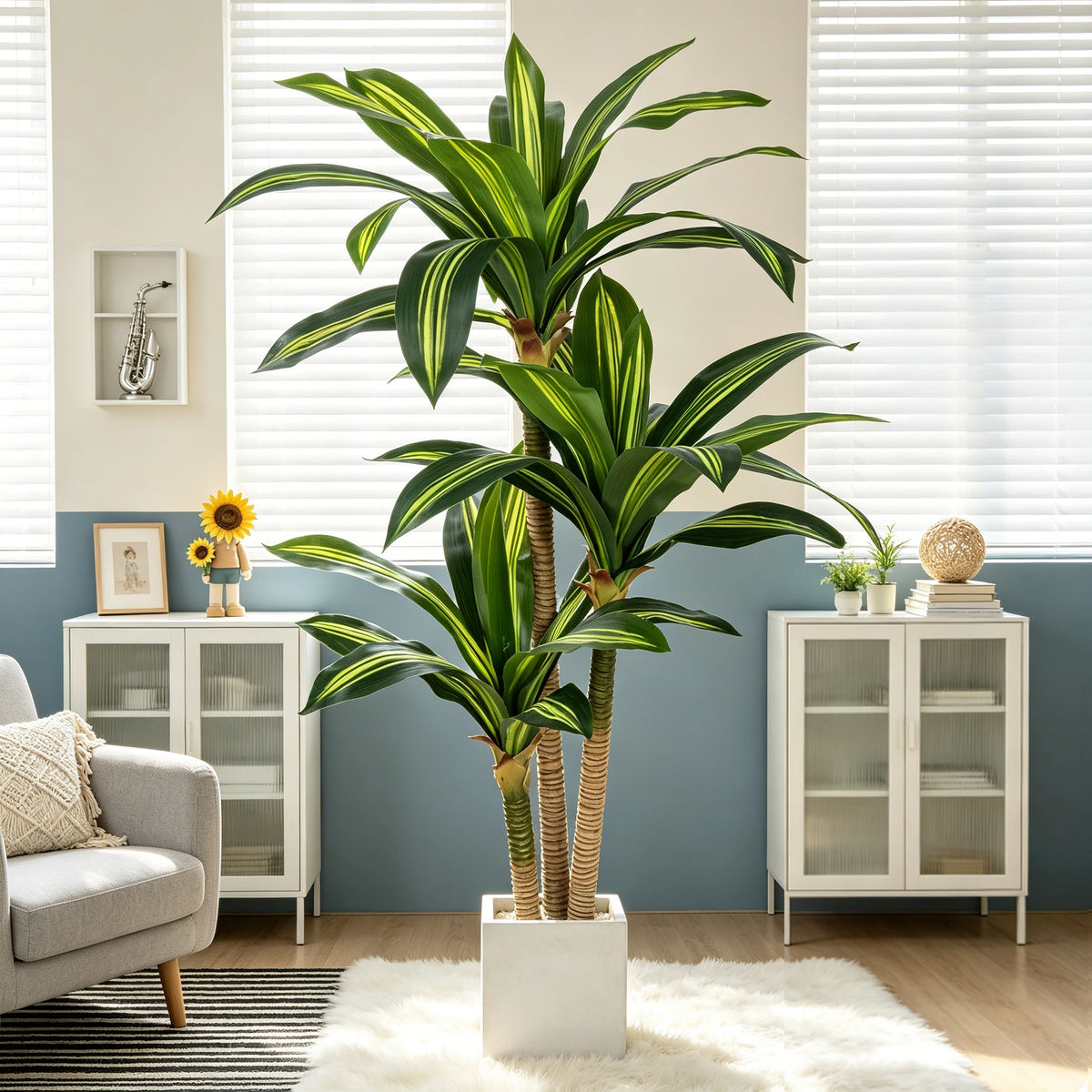 A tall artificial Dracaena tree in a white pot displayed in a modern living room setting.