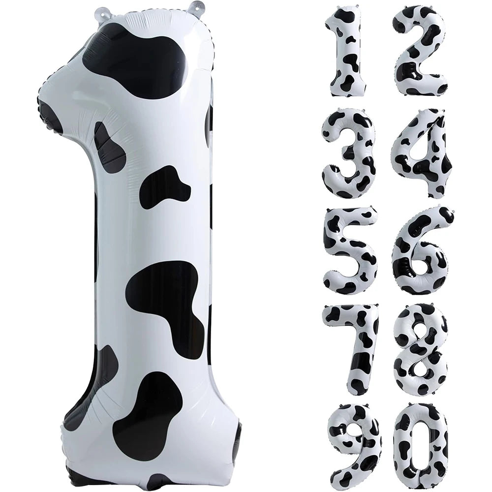A white foil balloon shaped like the number one with black cow print spots.