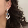 Silver pearl drop earrings featuring a blue eye motif and dangling pearls