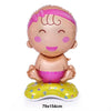 A pink foil baby bottle balloon decorated with a bow and resting on a yellow cushion.