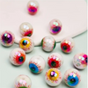 Un ensemble de dix perles de spasers oculaires en acrylique irisées avec des designs colorés et effrayants, éparpillées sur u
