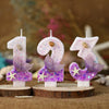 Three pink birthday candles shaped like numbers 1, 9, and 3 decorated with purple glitter and starfish flowers