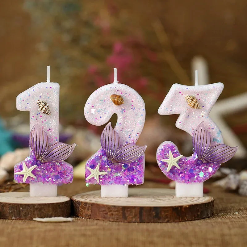 Three pink birthday candles shaped like numbers 1, 9, and 3 decorated with purple glitter and starfish flowers