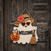 A wooden ghost door hanging featuring a witch hat design with a carved pumpkin and the word welcome.