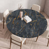 A round table covered with a dark gray marble print tablecloth featuring gold veining, set in a modern dining room.