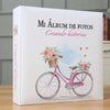 A white photo album titled Mi Álbum de Fotos Creando historias featuring a pink bicycle with flowers.