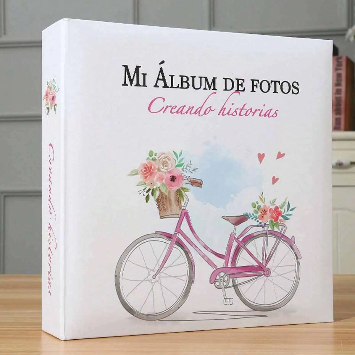 A white photo album titled Mi Álbum de Fotos Creando historias featuring a pink bicycle with flowers.