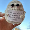 Hand-crocheted brown baseball bat doll with pink facial features holding a card that reads Life was all out of lemons so here