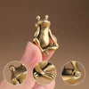 A hand holds a vintage brass frog statue desktop ornament, showing the detail of the animal sculpture.