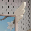 A light beige wing decoration mounted on a monitor frame against a white background with black dots.