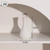 A white ceramic vase with a fluted design is shown on a shelf, casting a shadow.