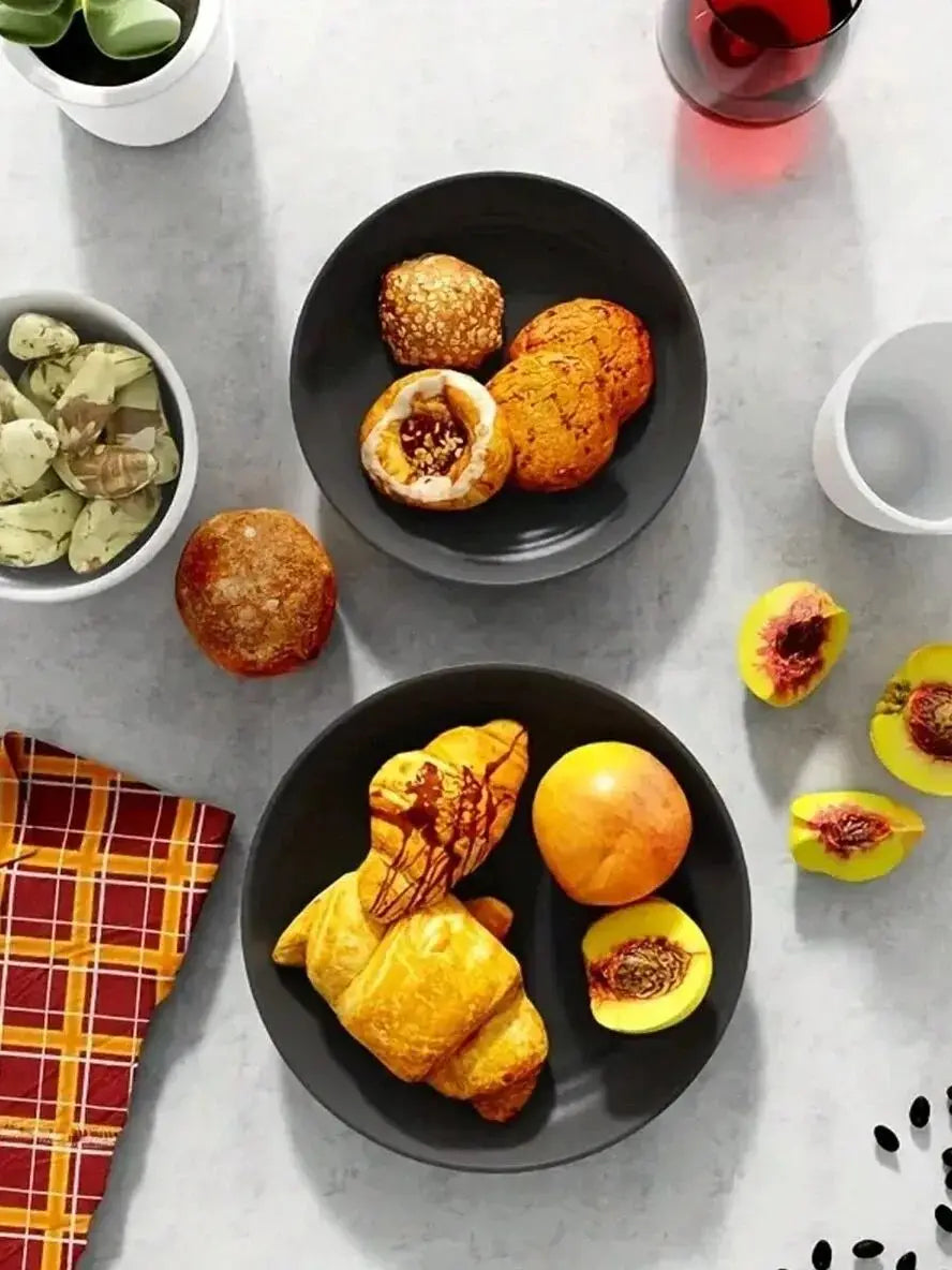 A dark plate holds several golden-brown baked goods, including muffins and pastries, on a light gray surface.