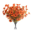 A bouquet of artificial orange and rust-colored flowers and eucalyptus stems displayed in a clear vase.