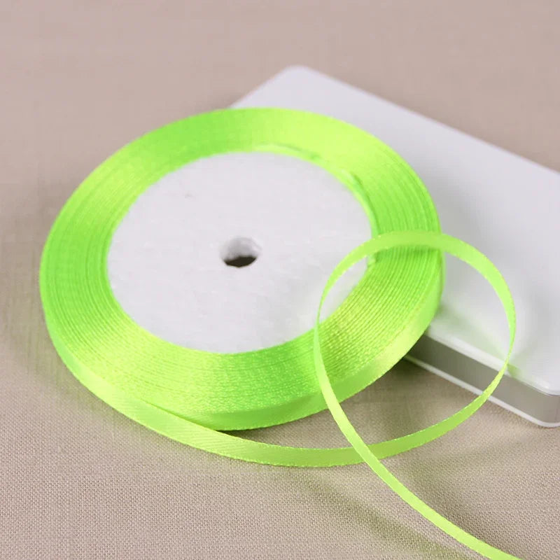 A roll of bright lime green satin ribbon on a white spool, ready for gift wrapping or crafts.