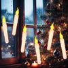 A close-up of glowing white LED floating candles hanging on a Christmas tree branch near a window.