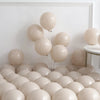 A collection of beige and cream balloons arranged in a balloon arch display against a white wall.