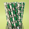 A bundle of green and white striped paper straws decorated with black and white soccer balls.