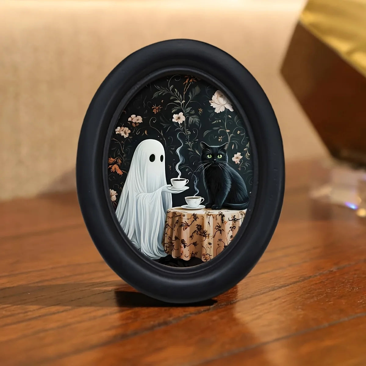 Oval framed wall art featuring a ghost and a black cat in a dark floral pattern.