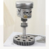 A silver steampunk skull sculpture featuring mechanical details and a gear mechanism on a stand.
