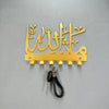 Gold Islamic Arabic blessing key holder with hooks mounted on a gray surface