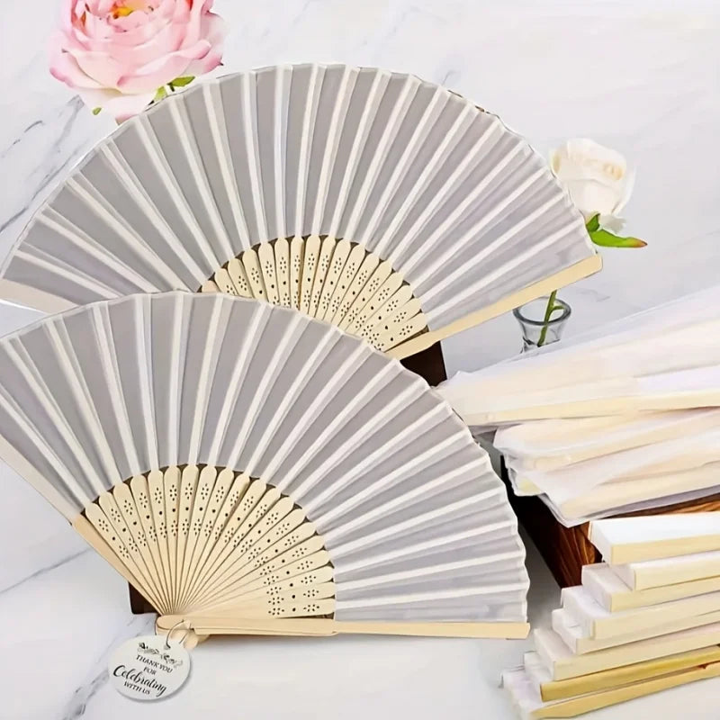 A set of bridal handheld folding fans in gray and natural wood tones displayed on a white marble surface.