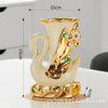A pair of elegant ceramic swan vases in cream and gold finish, displayed on a white surface.