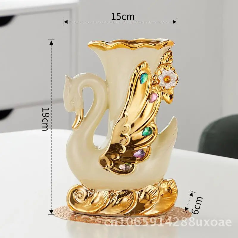 A pair of elegant ceramic swan vases in cream and gold finish, displayed on a white surface.