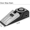 A silver door stop alarm device with a black casing and sensitivity adjustment dial.