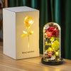 A rectangular box containing an eternal rose in a glass dome with a small figurine, illuminated by internal lights.