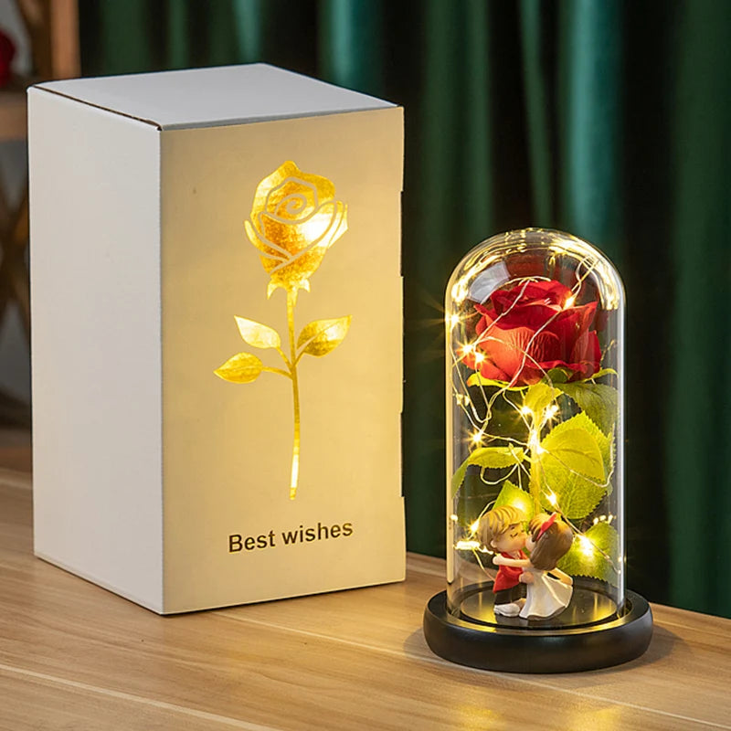 A rectangular box containing an eternal rose in a glass dome with a small figurine, illuminated by internal lights.