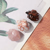 A display of natural crystal heart carvings in various colors including dark brown, white, and pink on a light background.