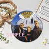 A set of collectible button pins featuring a Green Day album cover design.