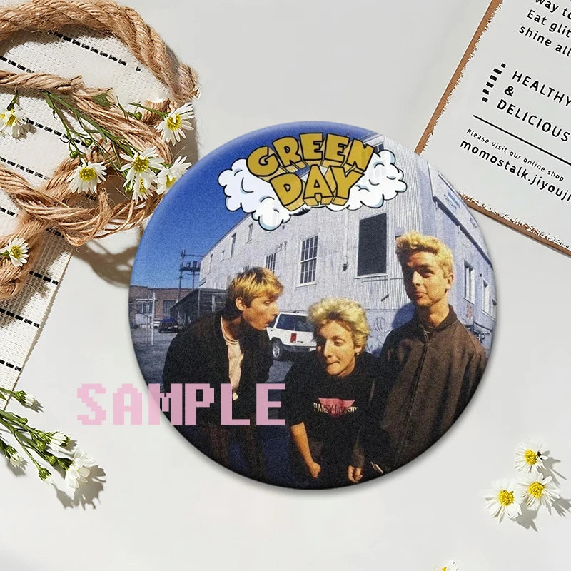A set of collectible button pins featuring a Green Day album cover design.