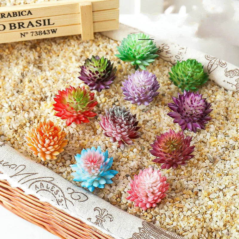 A collection of colorful mini artificial succulent bonsai balls in various shades of green, pink, and purple scattered on a l