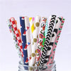 A collection of colorful striped and polka dot paper drinking straws in a glass container.
