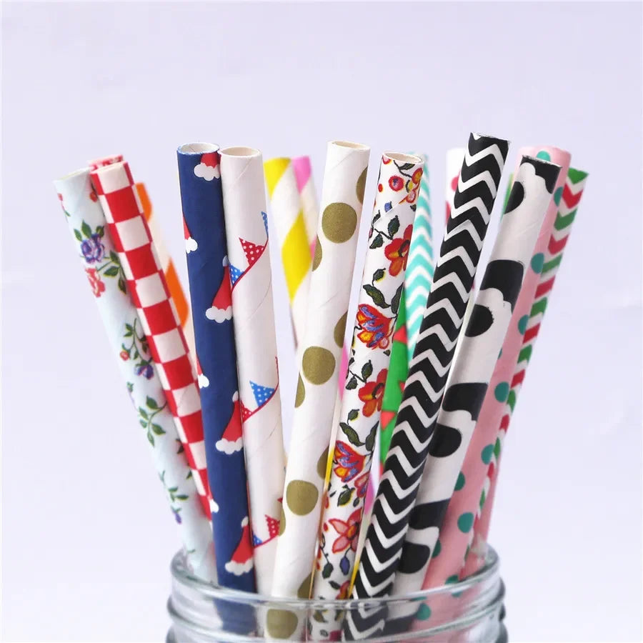 A collection of colorful striped and polka dot paper drinking straws in a glass container.