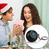 A woman is showing a black Magic 8 Ball keychain to a man in a festive holiday setting.